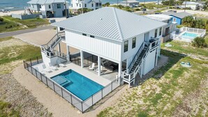 Une maison à deux étages avec piscine, située près de la plage et offrant une vue sur l’océan.