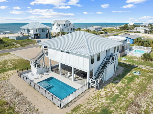 A two-story house with a pool, located near the beach with ocean views.