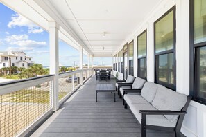 A covered balcony with a sofa, chairs, and a table.