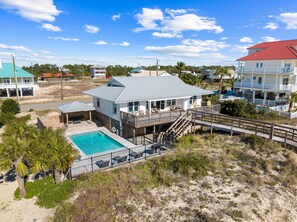 A beachfront property with a pool, a covered patio, and a two-story building with a red roof. - Sugar Magnolia: Beachfront SGI Home- Sleeps 12, Priv. Pool, Pet Friendly! (St. George Island)