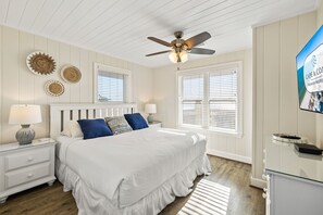 A bedroom with a bed, nightstands, a ceiling fan, and a TV on the wall. - Sugar Magnolia: Beachfront SGI Home- Sleeps 12, Priv. Pool, Pet Friendly! (St. George Island)