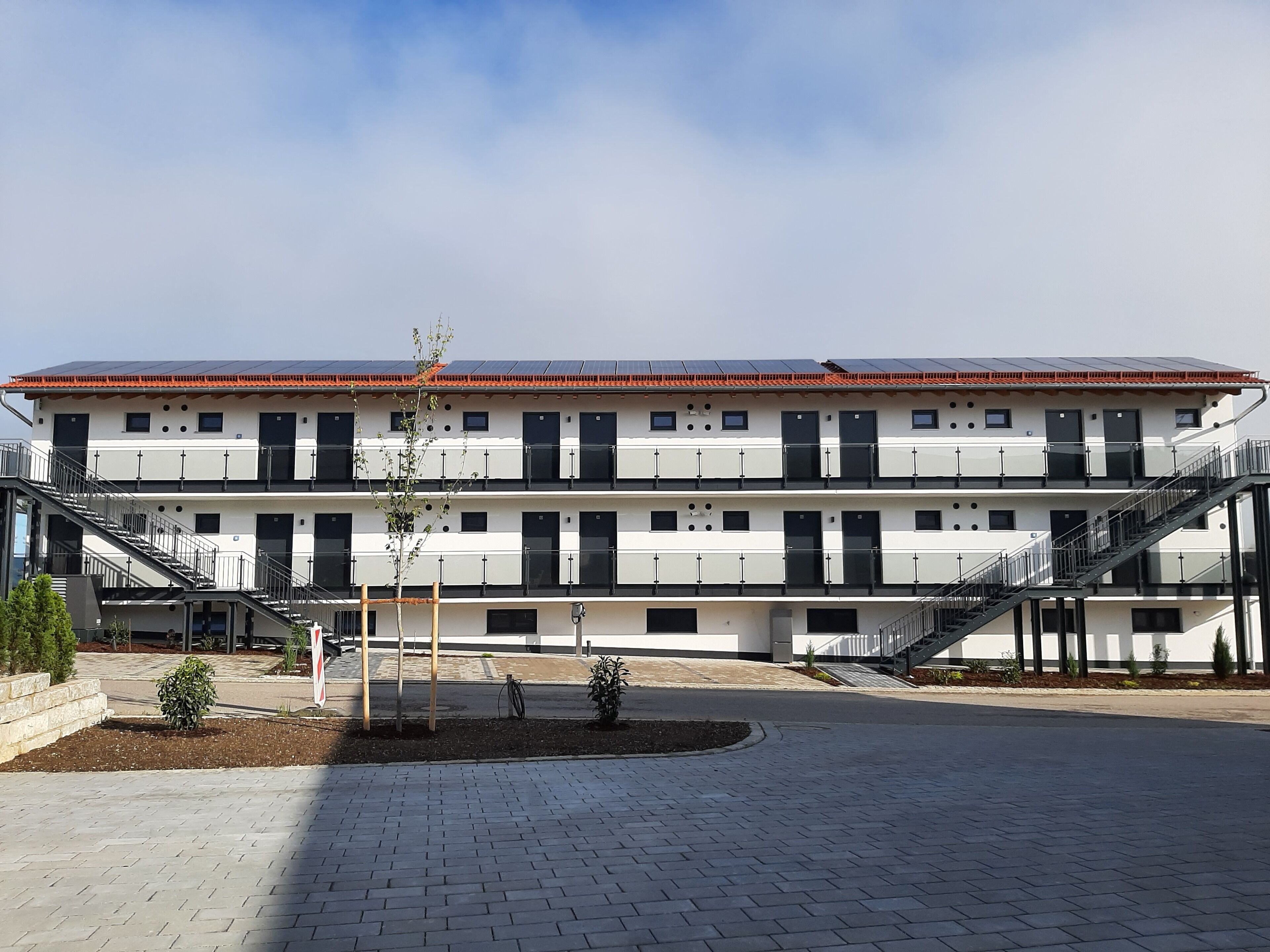 A multi-story building with a flat roof, multiple balconies, and a central courtyard.