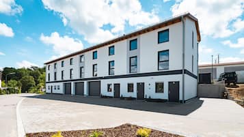 Stylish building with a flat roof and symmetrical facade, featuring a driveway and landscaped entrance.