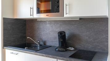 A modern kitchen with a built-in microwave, coffee maker, and a sleek countertop.