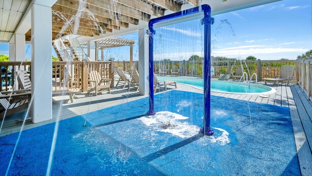 A pool area with a wooden deck, lounge chairs, and a hot tub. - Seven Seas: Book your stay and enjoy the Island's first Splash Pad! (St. George Island)