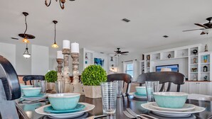 A dining area with a dark wooden table set for four, surrounded by chairs.
