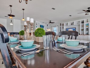 A dining area with a dark wooden table set for four, surrounded by chairs.