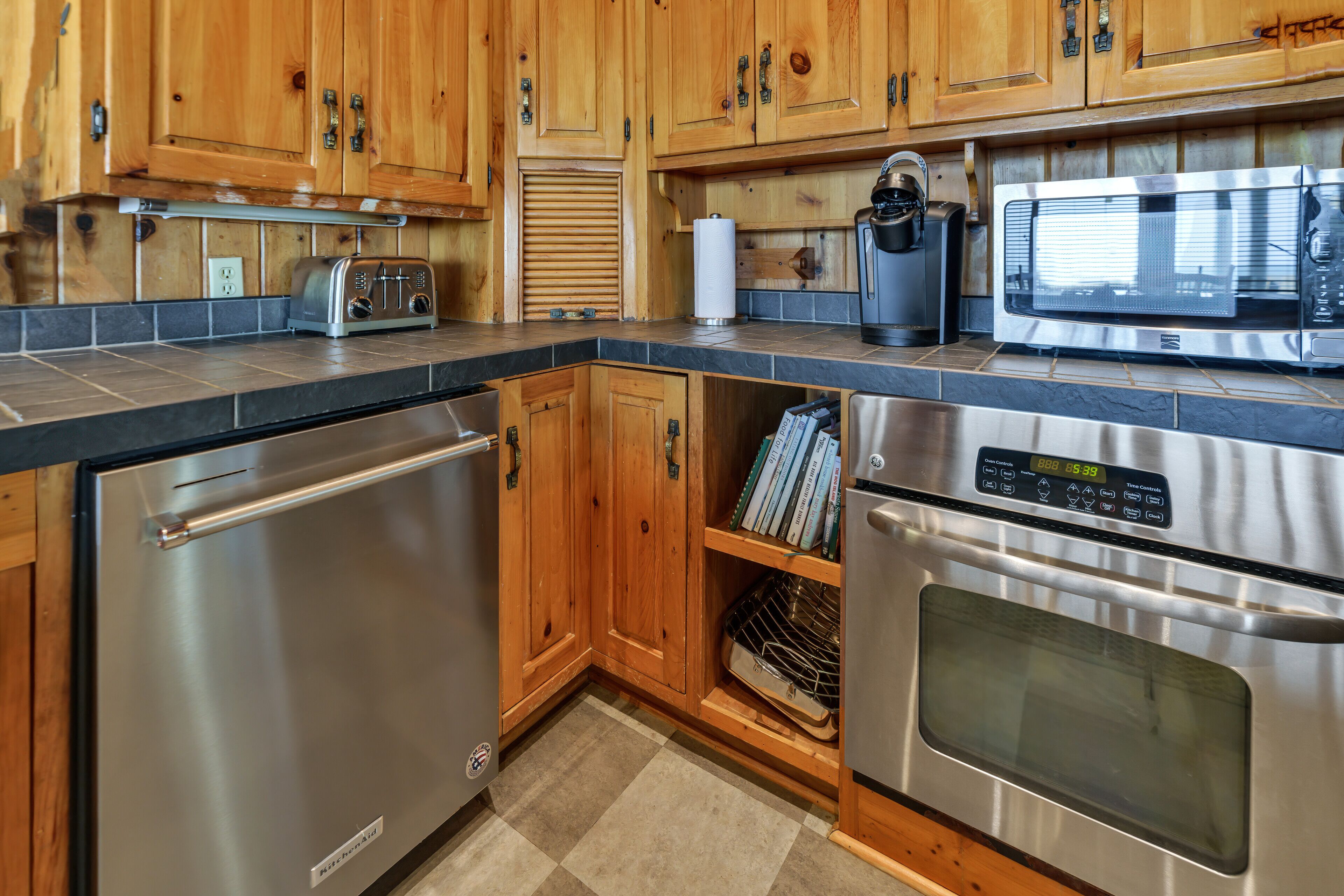 A kitchen with stainless steel appliances, wooden cabinets, and a tiled backsplash.