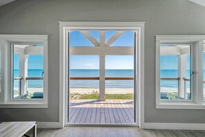 A room with a large open door leading to a balcony with a view of the beach and ocean. - Top of the Stretch: Premium Beachfront Property, 7 Bedrooms, Sleeps 22! (St. George Island)