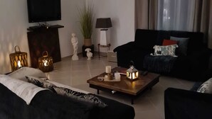 A living room with a sofa, a coffee table, a TV, and a lamp.