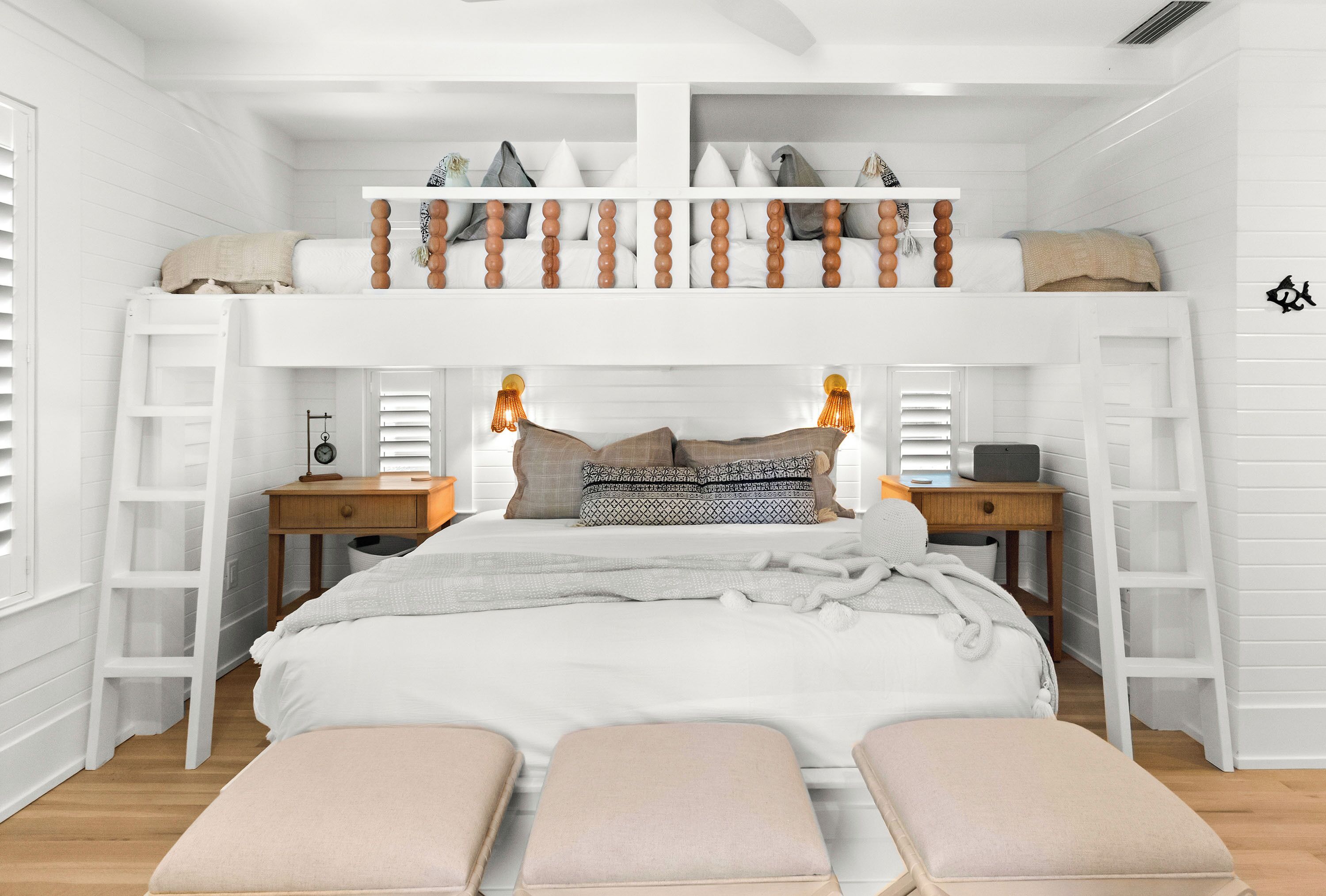 A bunk bed with a loft, bedside tables, lamps, and a bench.