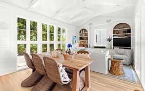 A dining area with wicker chairs, a wooden table, and a basket of items.