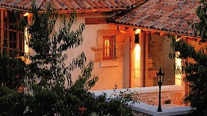Une maison rustique avec un toit en tuiles, des murs en pierre et une cheminée en pierre.
