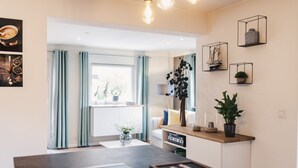 Eine moderne Küche mit einer zentralen Kochinsel, einem Essbereich und Blick auf das Wohnzimmer.