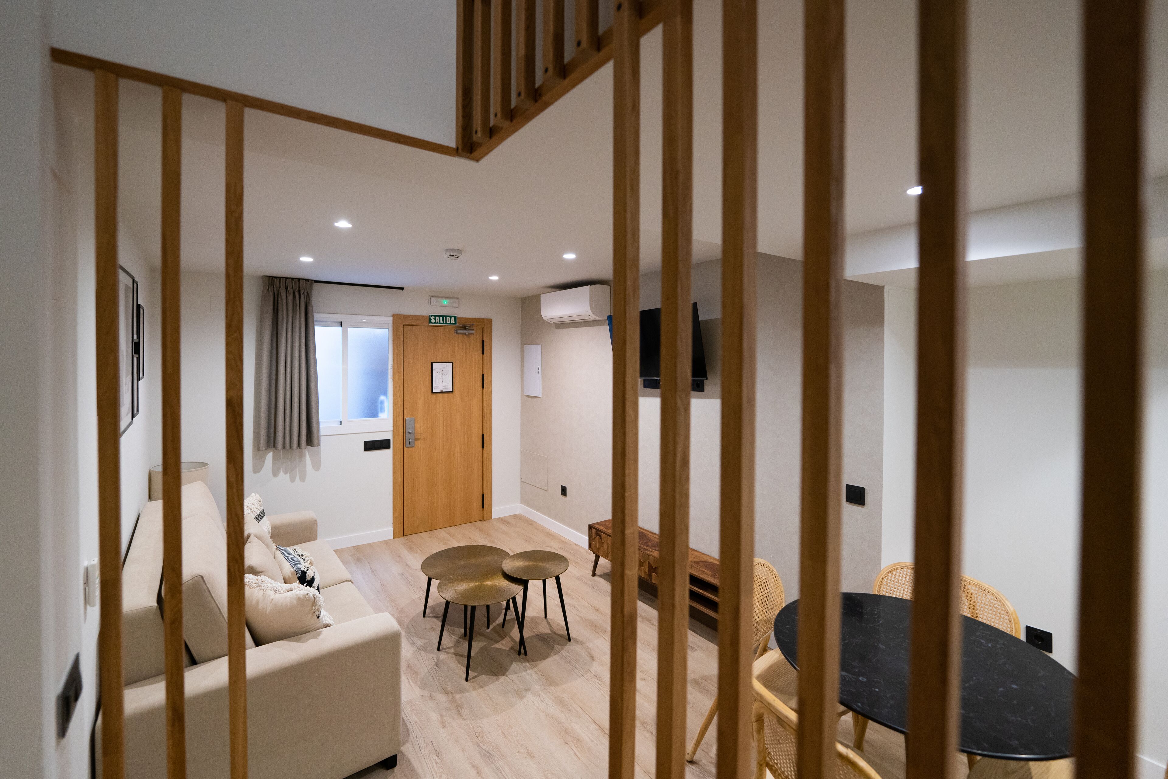 Ein modernes Interieur mit einer Couch, runden Tischen und einer Holztreppe.