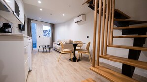 Une cuisine moderne avec des appareils électroménagers blancs, un coin repas avec une table ronde et des chaises, et un escalier avec des rampes en bois.