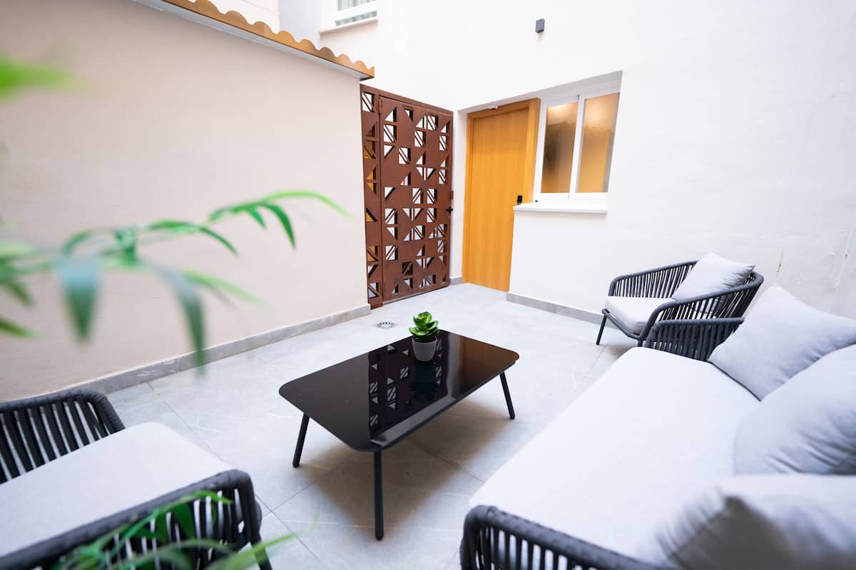 Un espace de détente extérieur moderne, comprenant un canapé, deux fauteuils, une table basse et une plante en pot.