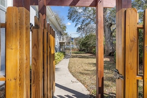 A wooden gate leading to a pathway with a house in the background.