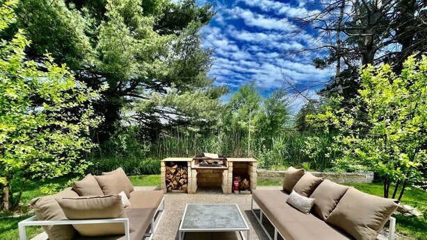 Un espacio al aire libre con asientos, un sofá, una mesa y una parrilla.