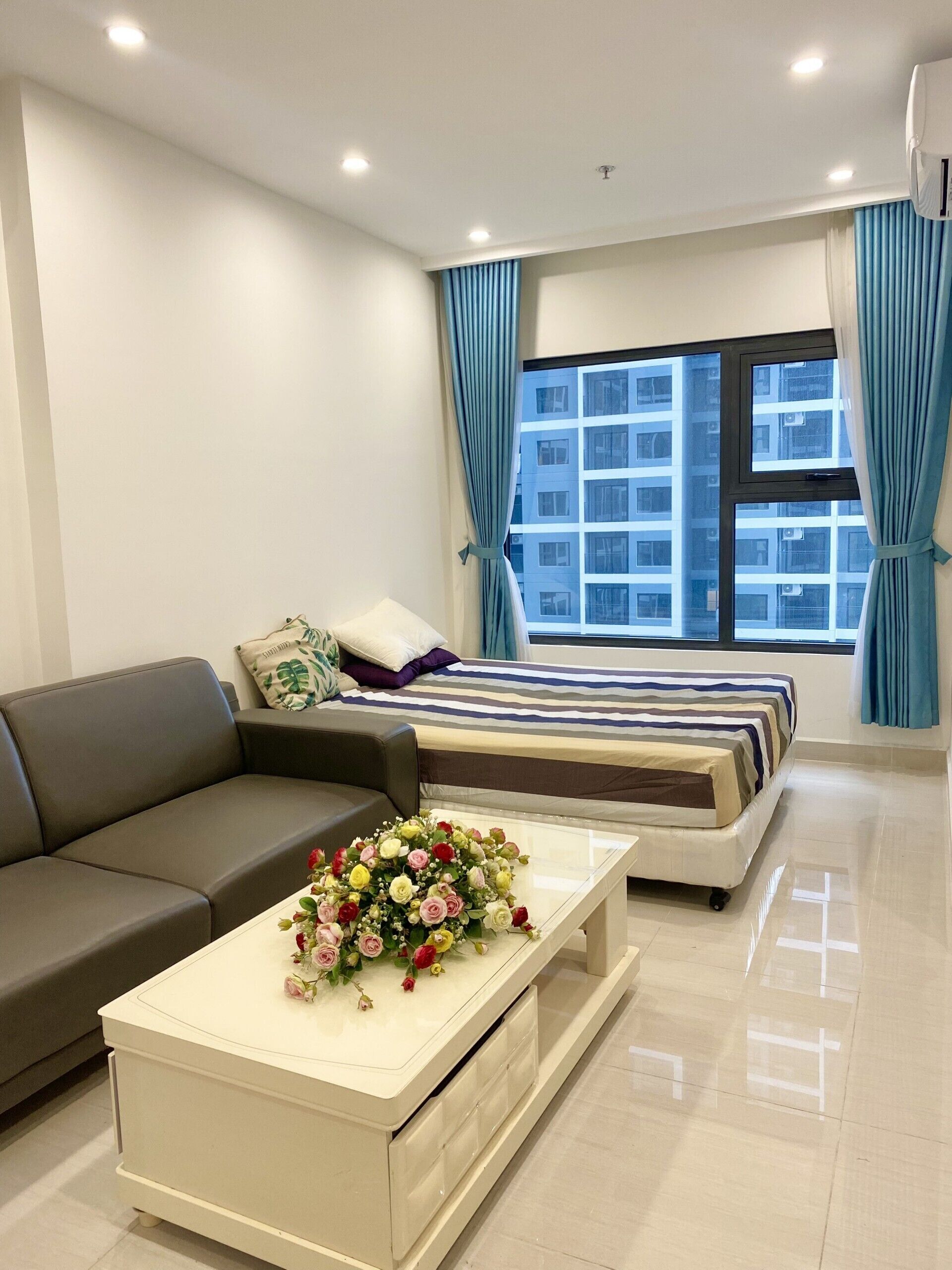 A modern bedroom with a bed, a sofa, and a coffee table with flowers.