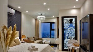 Ein modernes Hotelzimmer mit einem großen Bett, einer Couch, einem Esstisch und einem Fernseher.