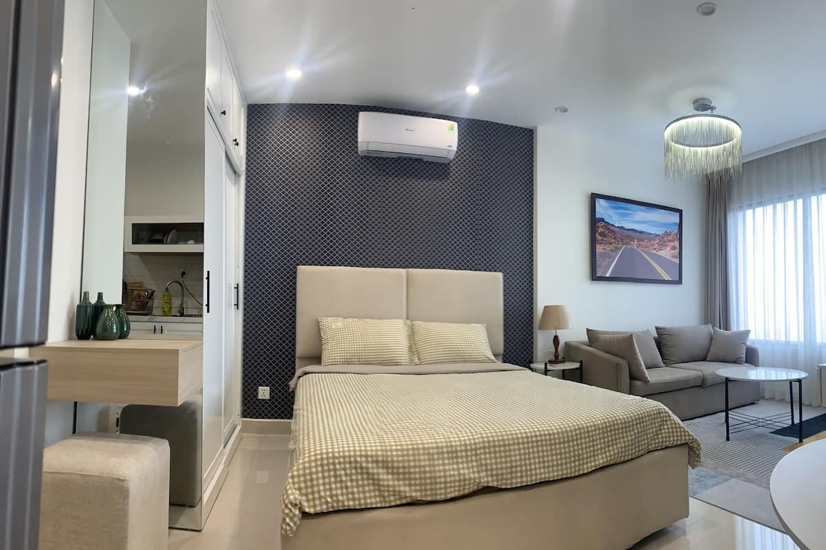 Een moderne hotelkamer met een groot bed, een slaapbank, een kleine tafel en uitzicht op een woestijnweg.