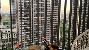 Ein Balkon mit zwei Kaffeetassen, einem Stuhl und Blick auf hohe Gebäude.