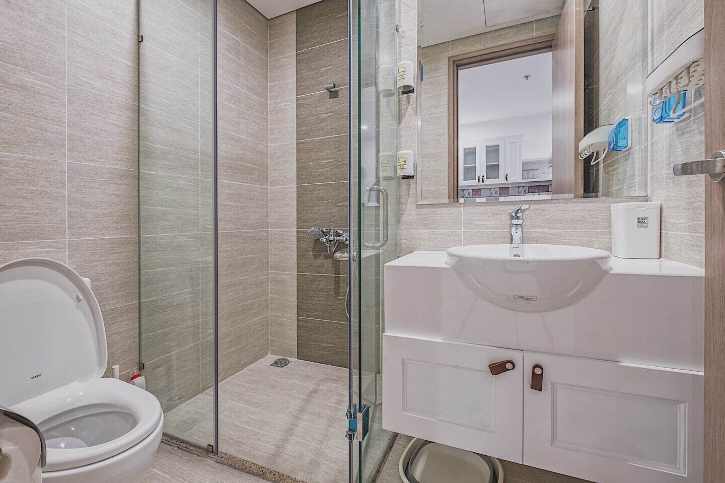 Ein modernes Badezimmer mit einer Duschkabine, einem weißen Waschbecken und einer Toilette.