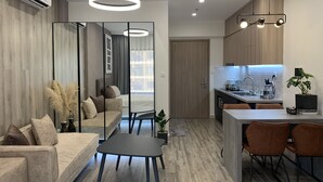 Eine moderne Wohnung mit Wohnbereich, Essbereich und Küche. Sie verfügt über ein Sofa, einen Esstisch und eine Küchenarbeitsplatte.