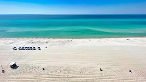 Een breed zandstrand met helder turquoise water en een strakblauwe lucht.
