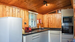 A kitchen with wooden walls, a white refrigerator, a red coffee maker, and a built-in oven. - 2 bedroom accommodation in Charlcot, near Masham (Charlcot, near Masham)