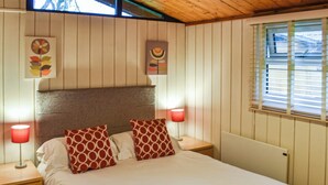 A neatly made bed with two pillows, a wooden headboard, and a nightstand with a lamp. - 2 bedroom accommodation in Charlcot, near Masham (Charlcot, near Masham)