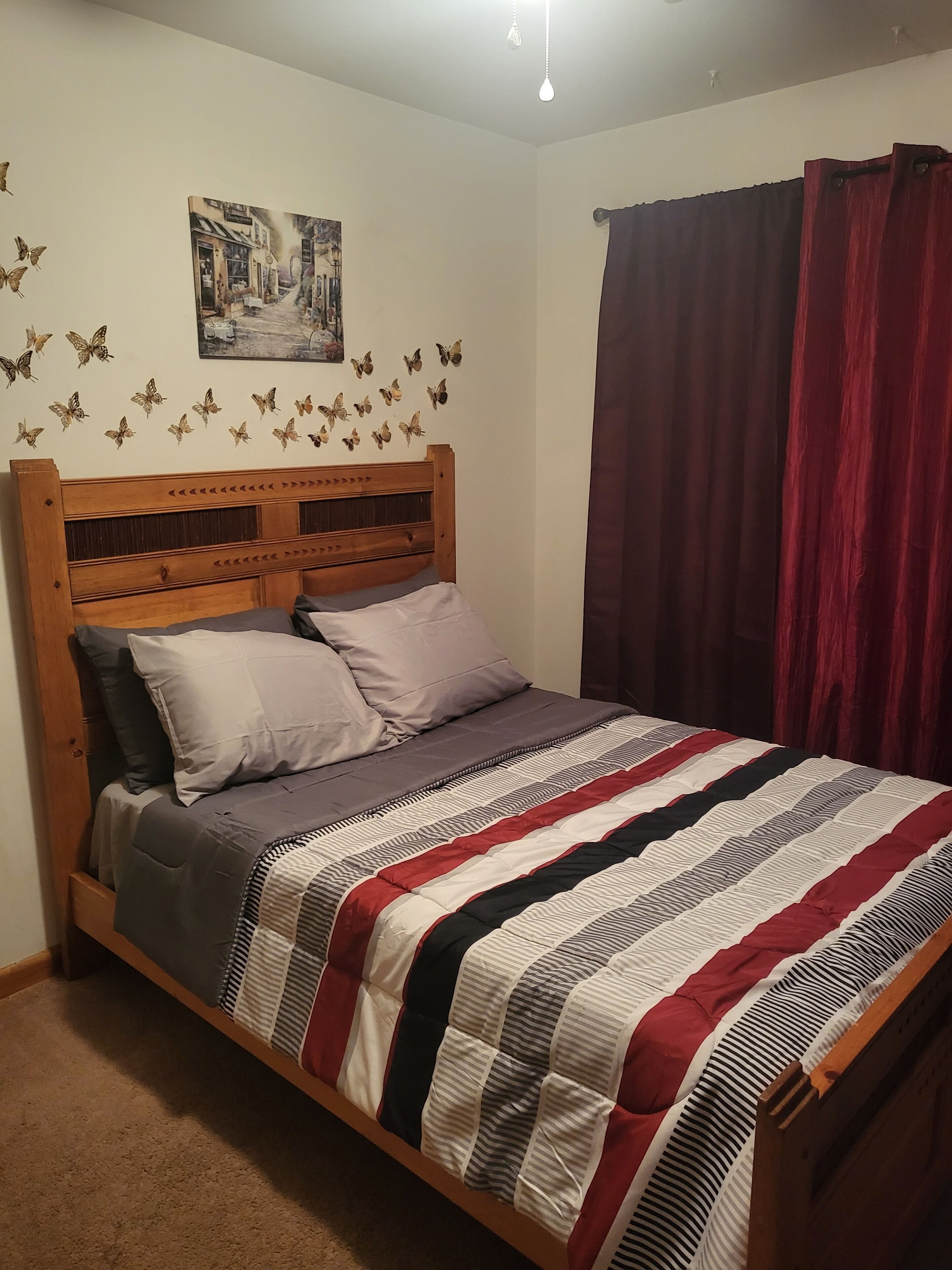 A bedroom with a wooden bed, a striped blanket, and butterfly wall decals.