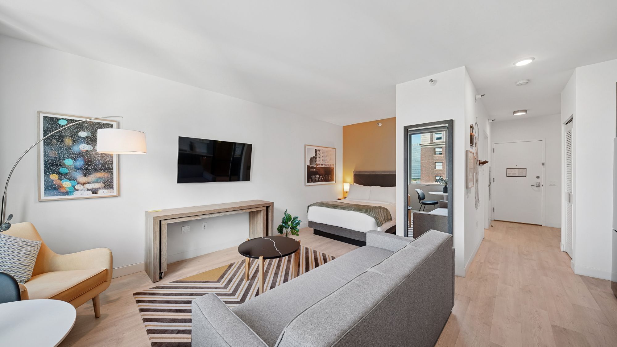 Una habitación de hotel moderna con sofá, televisor, chimenea y zona de comedor.