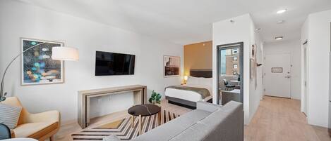 Et moderne hotelværelse med sofa, fjernsyn, pejs og spiseplads.