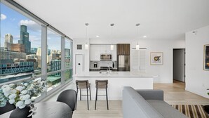A modern kitchen with a large island, bar stools, and a view of the city skyline. - Sentral Michigan Avenue (Chicago)