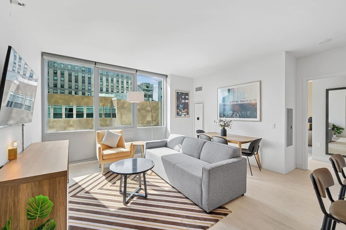 A modern living room with a sofa, a coffee table, and a dining area with a table and chairs.