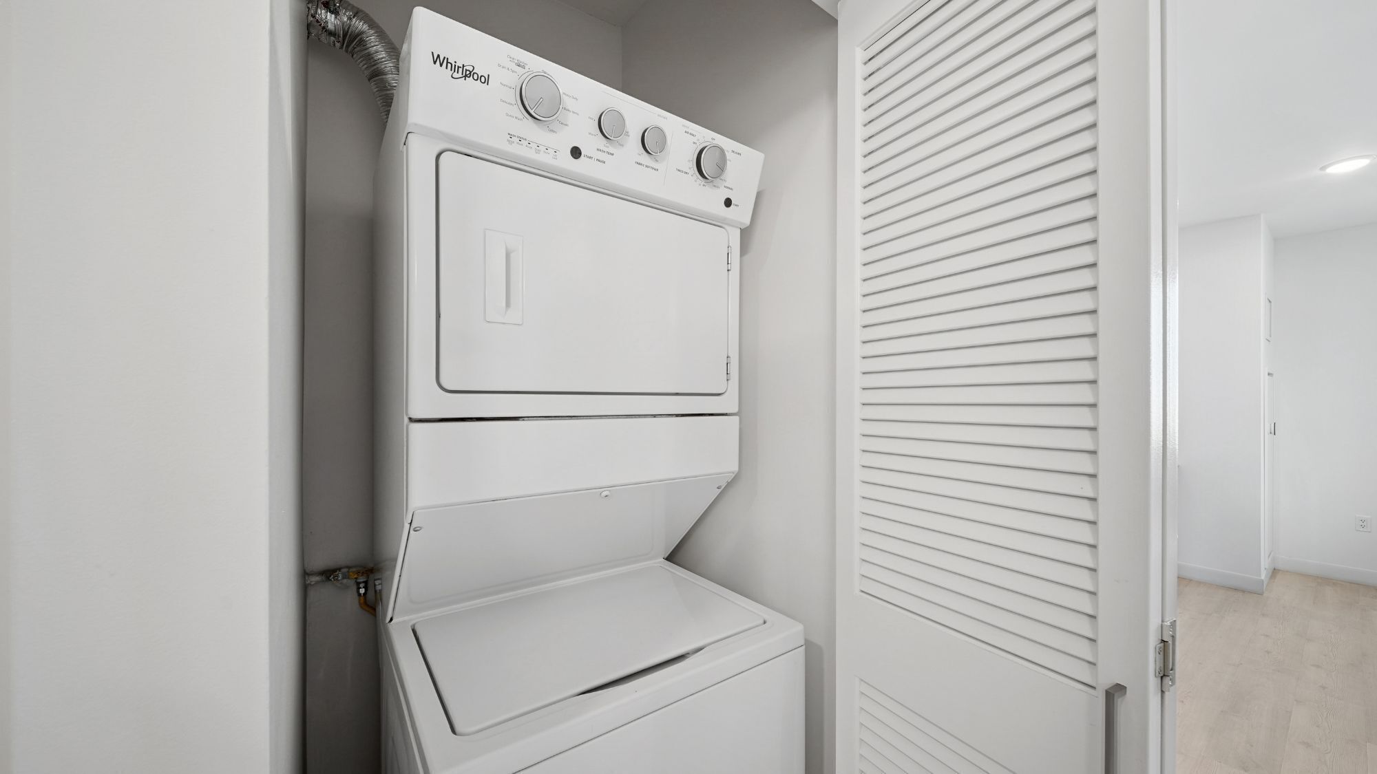 A white Whirlpool stacked washer and dryer in a room with a sliding door.