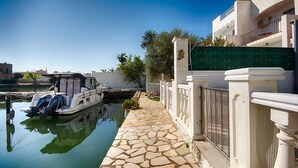 Un camí de pedra estret al costat d'un canal, amb una barca amarrada a l'esquerra.