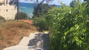 Un camino adoquinado que lleva a una zona costera con vista al mar y un edificio con múltiples ventanas.
