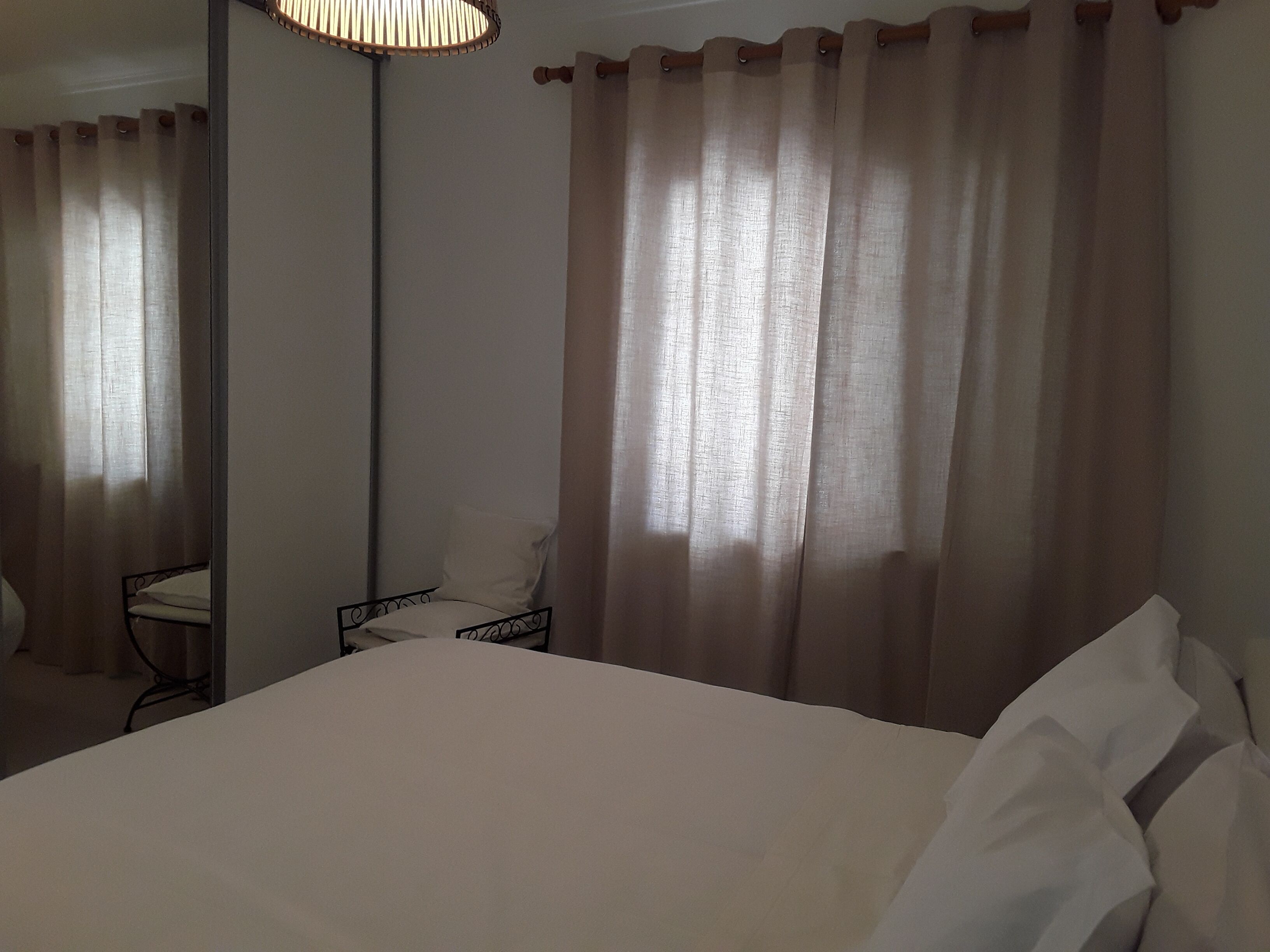 Une chambre d’hôtel avec un lit, une chaise, une table et des rideaux.