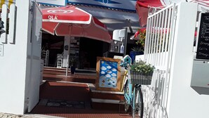 Una fachada con un paraguas rojo, una bicicleta y un letrero.