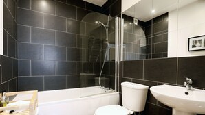 A modern bathroom with a bathtub, toilet, and sink. - Stable Cottage (Harrogate)