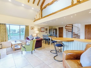 A spacious living area with a dining table, multiple chairs, a sofa, a bar area, and a staircase leading to an upper level. - 2 bedroom accommodation in Whitechapel, near Preston (Preston)
