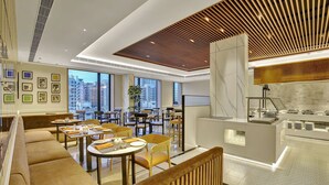 Un moderno vestíbulo de hotel con zonas de estar, un mostrador de recepción y grandes ventanales que ofrecen vistas a la ciudad.