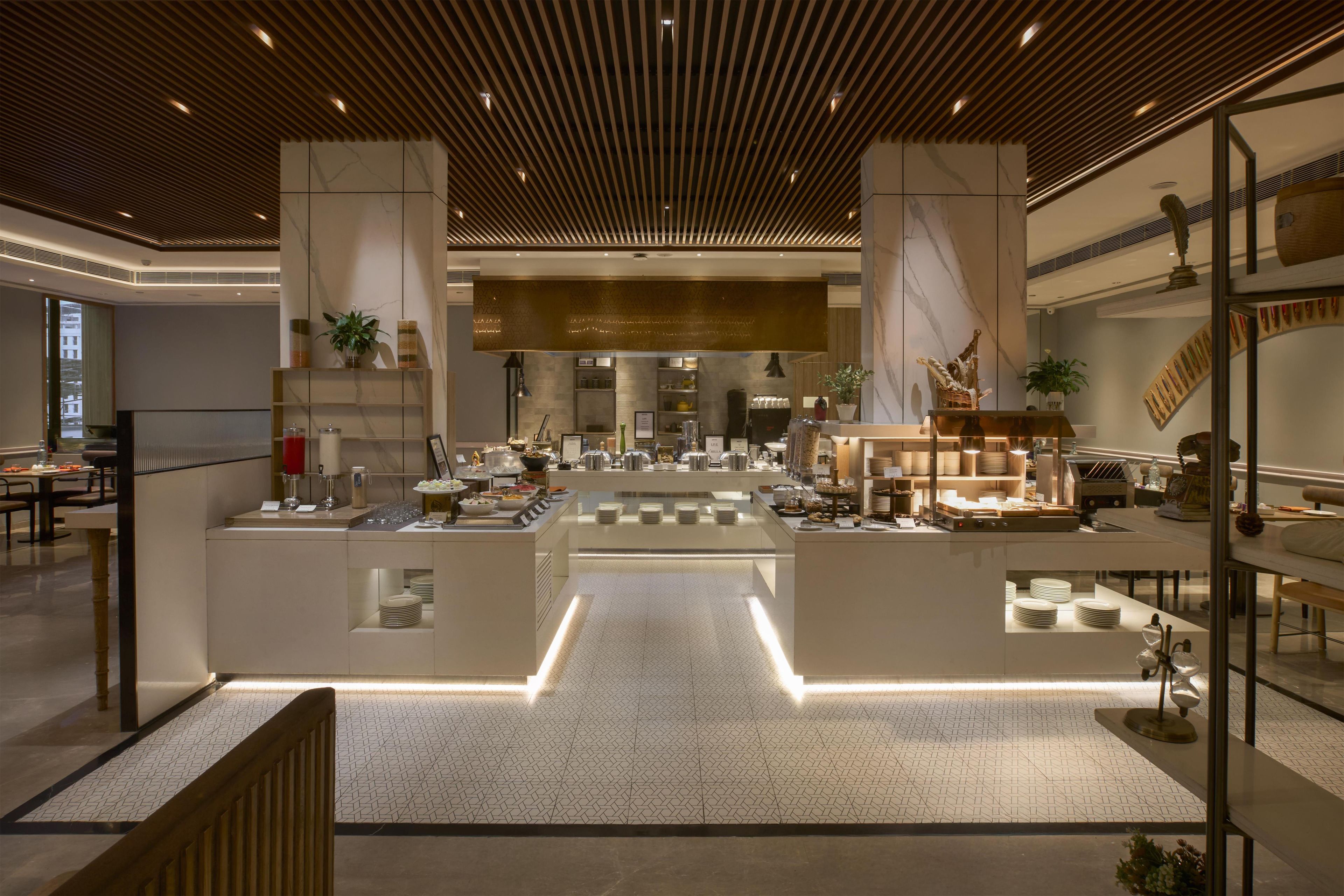 Un vestíbulo de hotel moderno con un mostrador de recepción central, zona de estar y vistas al comedor.