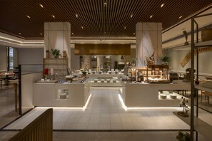 Un vestíbulo de hotel moderno con un mostrador de recepción central, zona de estar y vistas al comedor.