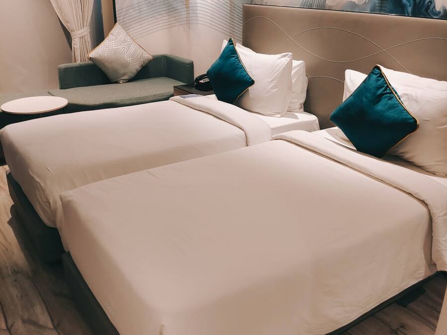 Una habitación de hotel moderna con dos camas, un sofá y una pequeña mesa redonda.