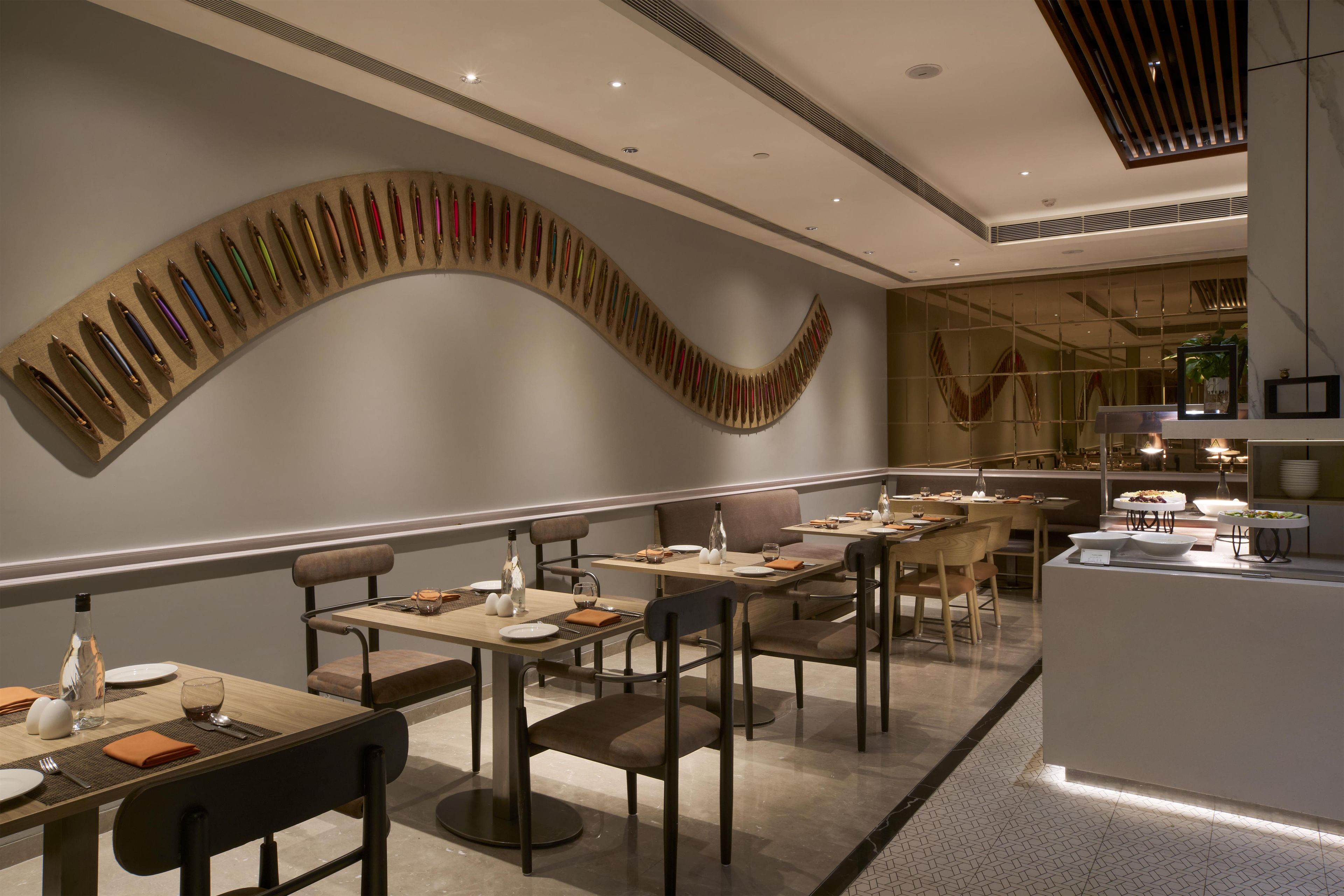 Un intérieur de restaurant moderne avec une longue table à manger, des chaises et une œuvre d’art murale originale.
