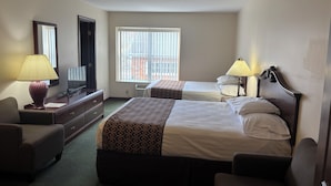 A hotel room with two beds, a desk, a chair, a TV, and a window. - Hotel Pratt- Cooperstown, NY- Baseball Central- Downtown- (Cooperstown)